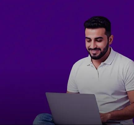 smiling man using laptop on purple background