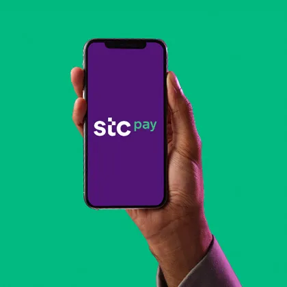 stc pay App - hand with mobile phone and on the screen it says stc pay logo